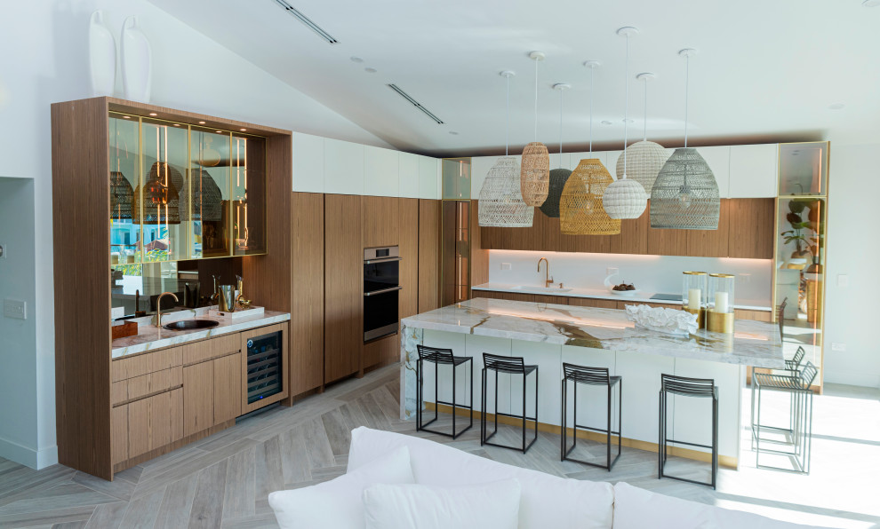 Mid-sized modern l-shaped open plan kitchen in Miami with an undermount sink, flat-panel cabinets, medium wood cabinets, marble benchtops, white splashback, marble splashback, panelled appliances, ceramic floors, with island, brown floor and beige benchtop.