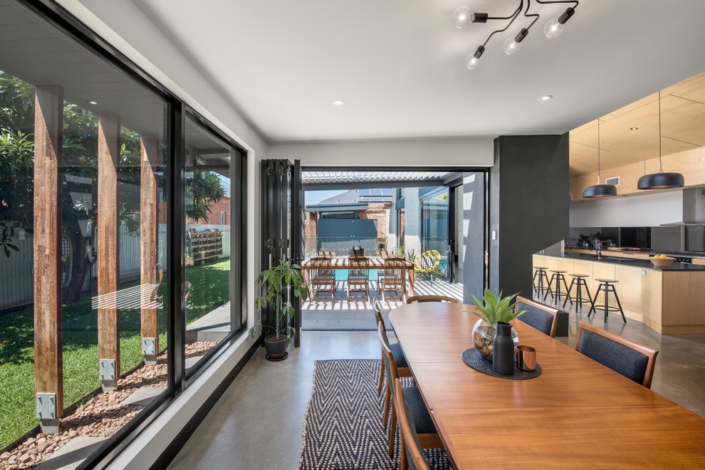 This is an example of a mid-sized contemporary open plan dining in Adelaide with white walls, concrete floors and grey floor.