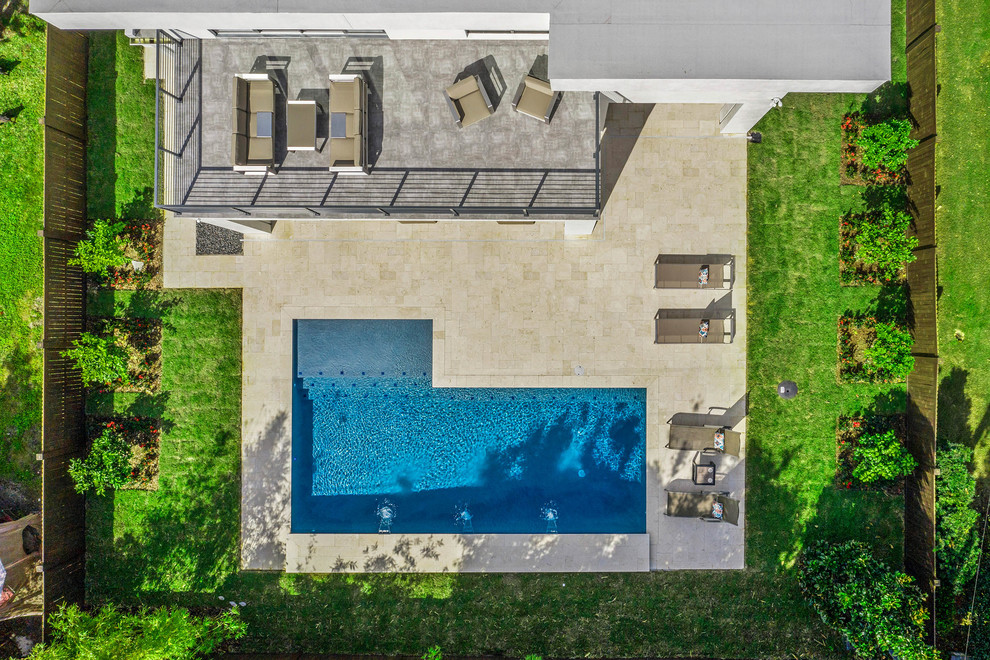 This is an example of a large contemporary backyard l-shaped lap pool in Orlando with concrete pavers.