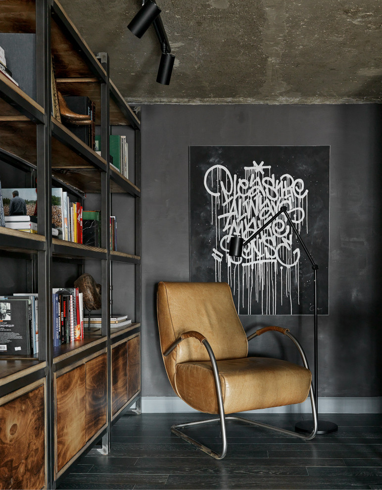 Foto på ett mellanstort industriellt arbetsrum, med ett bibliotek, svarta väggar, mellanmörkt trägolv, ett fristående skrivbord och blått golv