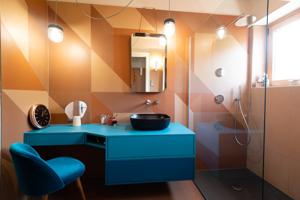 Photo of a mid-sized midcentury master bathroom in Strasbourg with beaded inset cabinets, blue cabinets, a curbless shower, orange tile, cement tile, orange walls, cement tiles, a vessel sink, laminate benchtops, orange floor, an open shower, blue benchtops, a two-piece toilet, a niche, a single vanity, a floating vanity, wallpaper, brick walls and a freestanding tub.