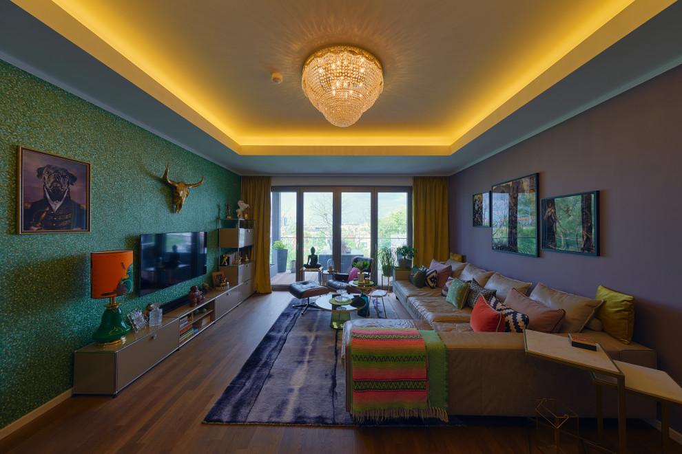 Foto de salón para visitas abierto actual grande con paredes verdes, suelo laminado, televisor colgado en la pared, suelo marrón, bandeja y papel pintado
