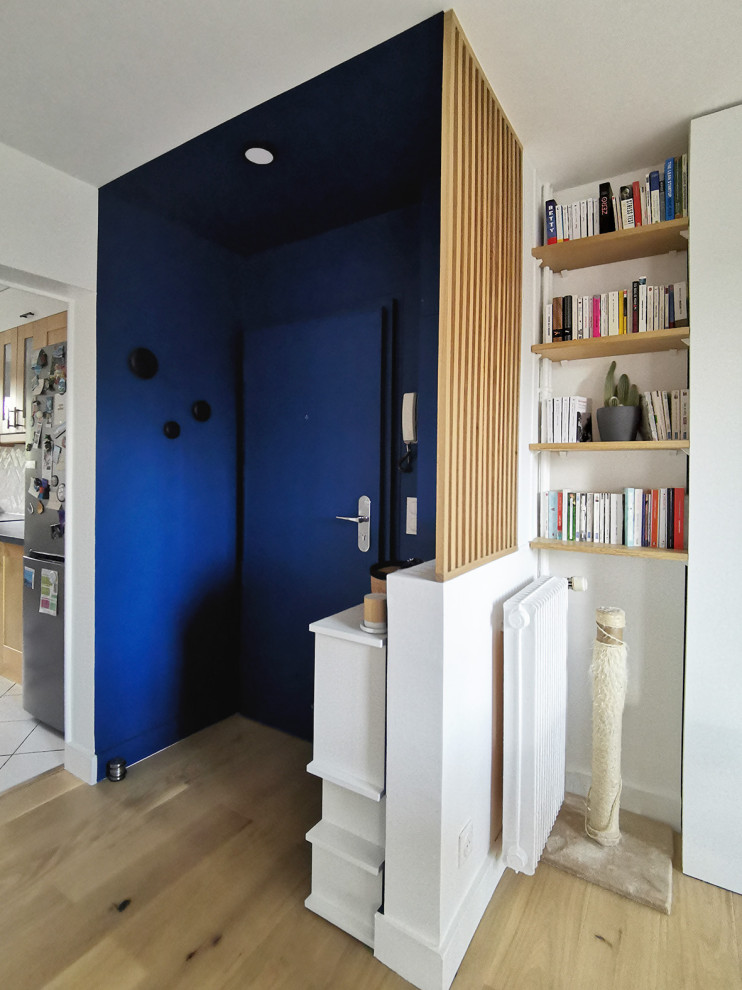 Cette image montre un petit hall d'entrée design avec un mur bleu, parquet clair, une porte simple et une porte bleue.