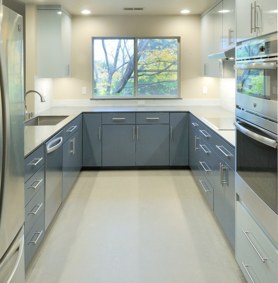 This is an example of a mid-sized contemporary u-shaped separate kitchen in Sacramento with an undermount sink, flat-panel cabinets, blue cabinets, solid surface benchtops, grey splashback, stone tile splashback, stainless steel appliances, linoleum floors and no island.