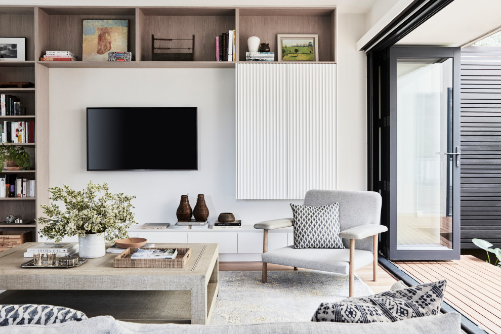 Immagine di un grande soggiorno stile marino aperto con libreria, pareti bianche, parquet chiaro e TV a parete