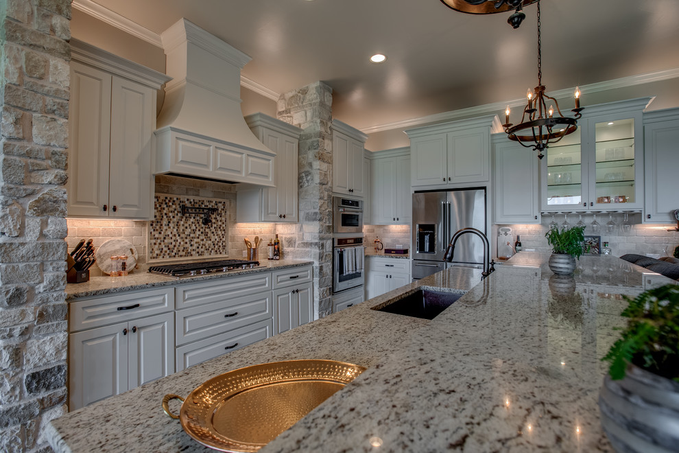 Design ideas for a large transitional l-shaped kitchen in Austin with raised-panel cabinets, white cabinets, granite benchtops, grey splashback, stone tile splashback, stainless steel appliances, dark hardwood floors, with island, brown floor and grey benchtop.