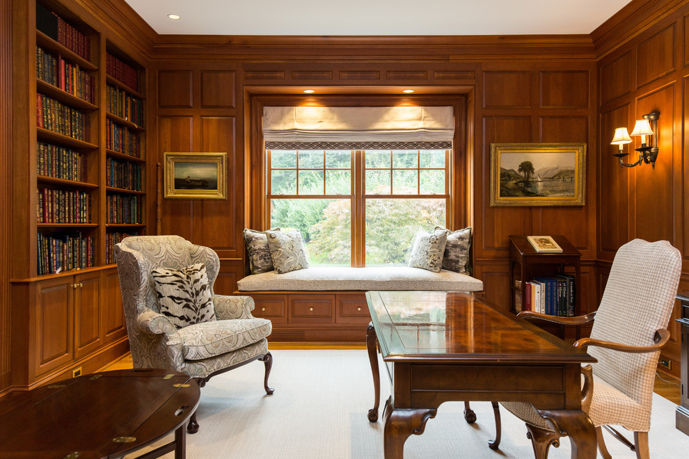 This is an example of a mid-sized traditional home office in New Orleans with a library, brown walls, dark hardwood floors, a standard fireplace, a wood fireplace surround, a freestanding desk and brown floor.