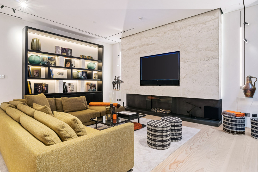 Contemporary open plan living room in London with white walls, light hardwood flooring, a standard fireplace, a stone fireplace surround, a wall mounted tv and beige floors.
