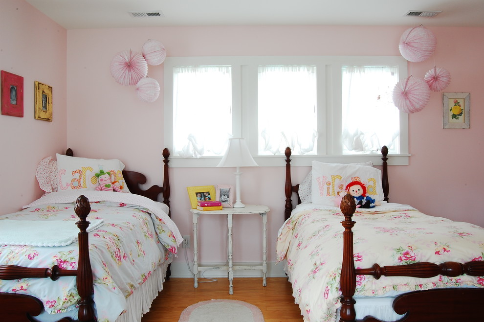 This is an example of a country kids' bedroom for girls in New York with pink walls and medium hardwood floors.
