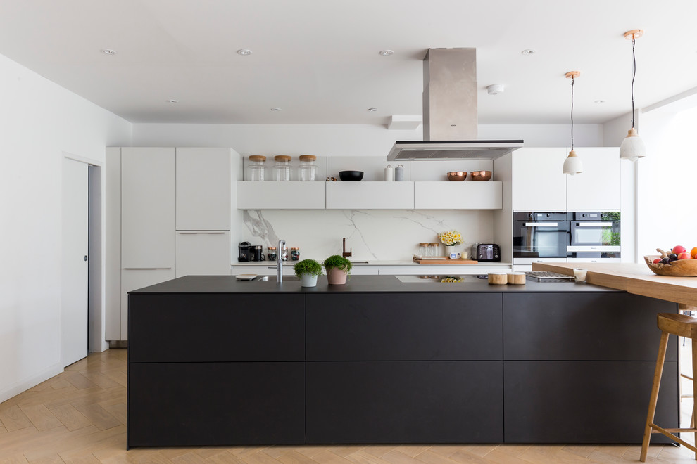 Design ideas for a large contemporary galley eat-in kitchen in London with an undermount sink, flat-panel cabinets, white cabinets, white splashback and with island.