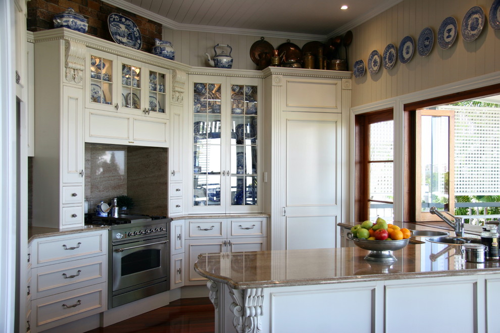 Mid-sized country eat-in kitchen in Brisbane with a drop-in sink, recessed-panel cabinets, granite benchtops, stone slab splashback, stainless steel appliances and dark hardwood floors.