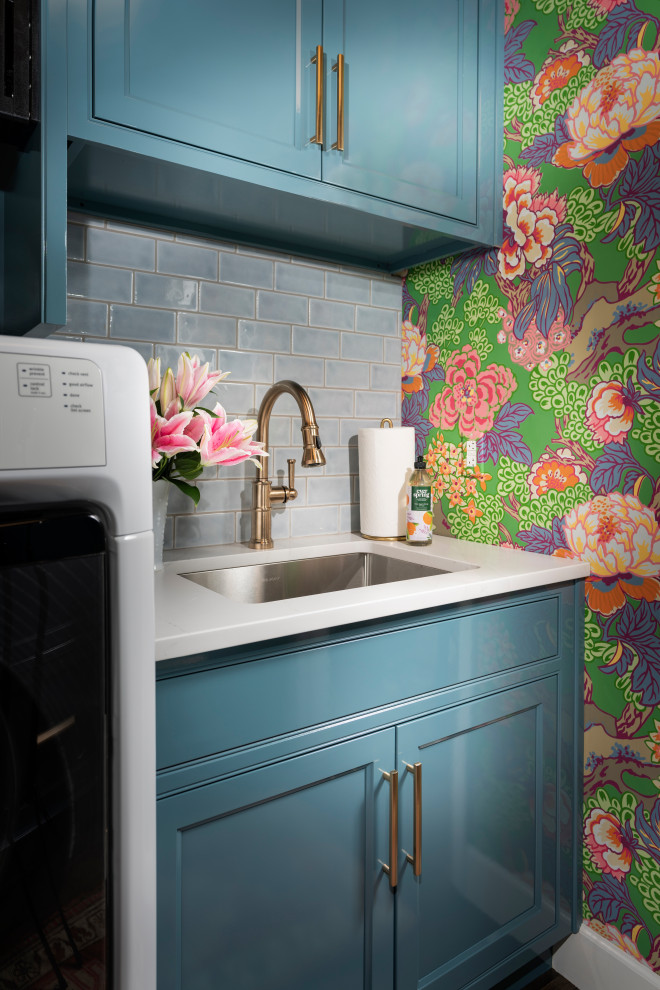 Inspiration for a mid-sized eclectic galley dedicated laundry room in Other with an undermount sink, beaded inset cabinets, blue cabinets, quartz benchtops, blue splashback, subway tile splashback, blue walls, dark hardwood floors, a side-by-side washer and dryer, white benchtop, wallpaper and wallpaper.