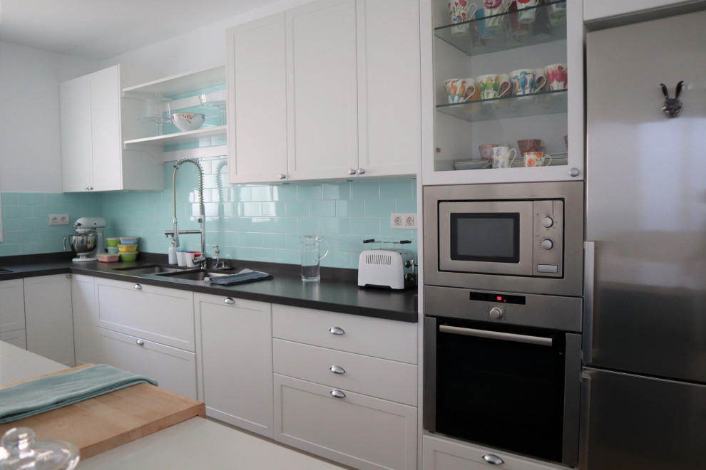 Large beach style l-shaped open plan kitchen in Other with a double-bowl sink, shaker cabinets, white cabinets, quartz benchtops, green splashback, ceramic splashback, stainless steel appliances, porcelain floors, with island, brown floor and grey benchtop.