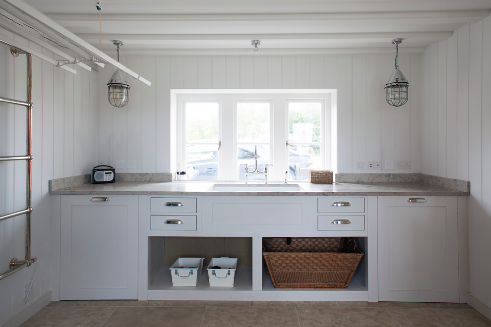 Mid-sized beach style laundry room in Wiltshire with an undermount sink, shaker cabinets, white cabinets and white walls.