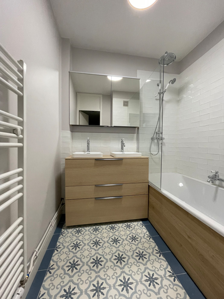 This is an example of a small scandi ensuite wet room bathroom in Lille with flat-panel cabinets, brown cabinets, a submerged bath, a two-piece toilet, white tiles, ceramic tiles, grey walls, cement flooring, a built-in sink, wooden worktops, blue floors, a hinged door, brown worktops, double sinks and a built in vanity unit.