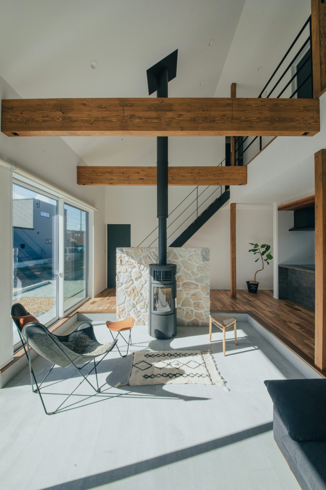 This is an example of a contemporary living room in Other with white walls, a wood stove, a stone fireplace surround, grey floor, wallpaper, concrete floors and exposed beam.