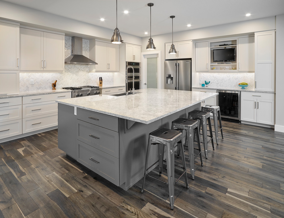 Mid-sized transitional brown floor and dark wood floor kitchen photo in Edmonton with white cabinets, quartz countertops, white backsplash, ceramic backsplash, stainless steel appliances, an island, white countertops and shaker cabinets