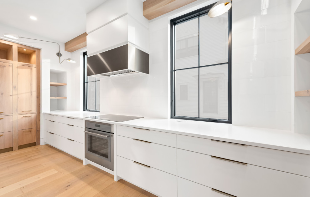 Inspiration for a large transitional u-shaped light wood floor and brown floor open concept kitchen remodel in Chicago with an undermount sink, flat-panel cabinets, white cabinets, quartz countertops, white backsplash, porcelain backsplash, colored appliances, an island and black countertops