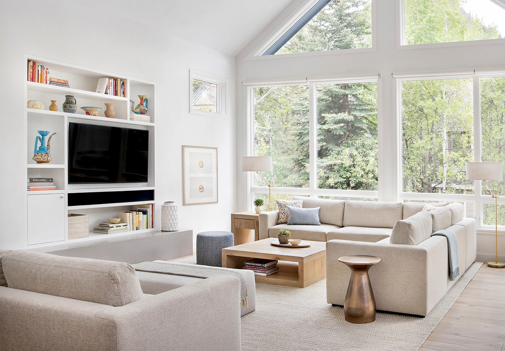 Photo of a scandinavian open concept family room with a library, white walls, light hardwood floors, no fireplace and a built-in media wall.