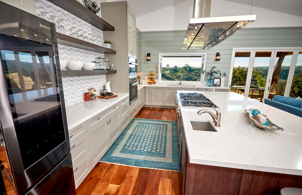 Open concept kitchen - large transitional l-shaped medium tone wood floor and brown floor open concept kitchen idea in Denver with an undermount sink, recessed-panel cabinets, gray cabinets, quartz countertops, white backsplash, marble backsplash, stainless steel appliances, an island and white countertops