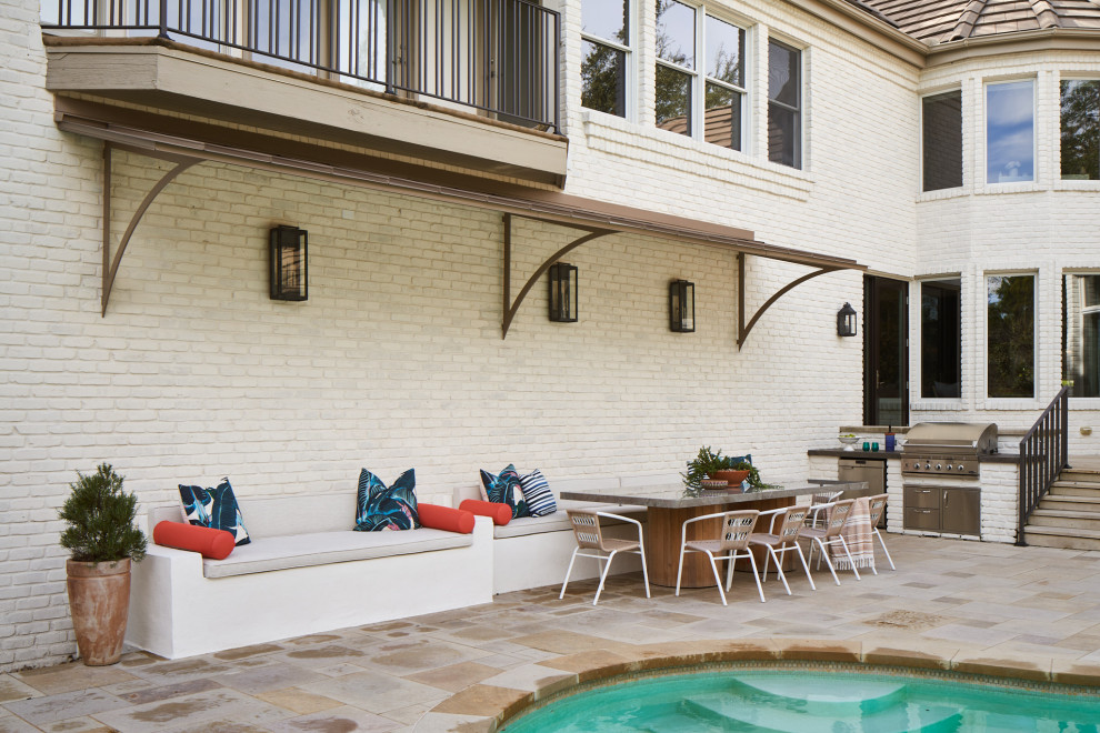 Patio kitchen - large transitional backyard stone patio kitchen idea in Austin with an awning