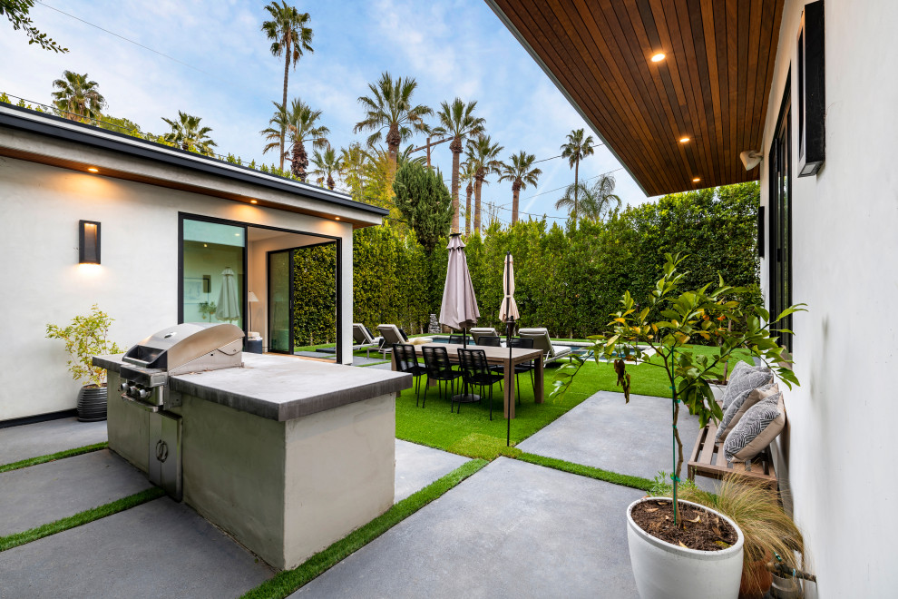 Inspiration for a mid-sized contemporary side yard patio in Los Angeles with concrete pavers, a roof extension and an outdoor kitchen.