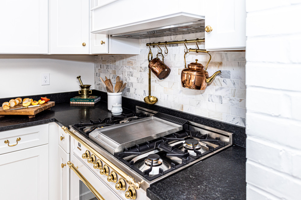 Inspiration for a small l-shaped kitchen pantry in Baltimore with a submerged sink, shaker cabinets, white cabinets, marble worktops, white splashback, marble splashback, stainless steel appliances, porcelain flooring, an island, beige floors, black worktops and exposed beams.