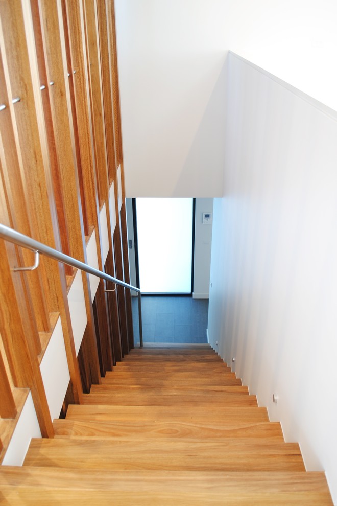 Small modern wood straight staircase in Melbourne with wood risers and metal railing.