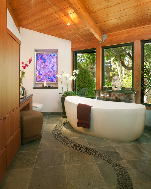 Large contemporary master bathroom in Austin with flat-panel cabinets, light wood cabinets, a freestanding tub, a two-piece toilet, white walls, slate floors and solid surface benchtops.
