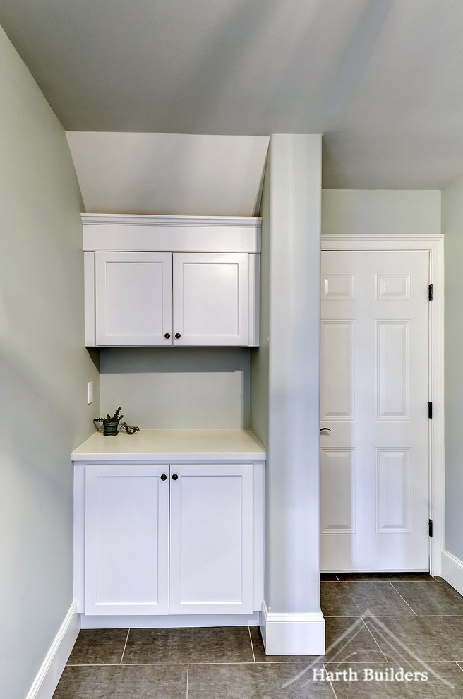 This is an example of a small transitional l-shaped utility room in Philadelphia with an undermount sink, recessed-panel cabinets, white cabinets, solid surface benchtops, blue walls, vinyl floors and a side-by-side washer and dryer.