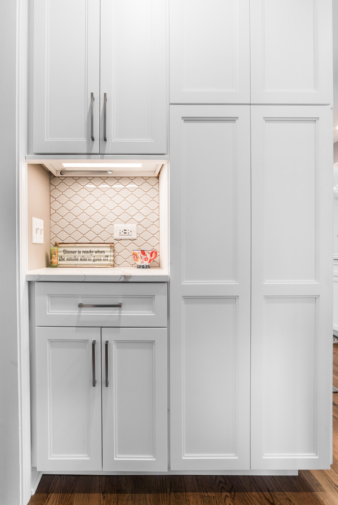 Inspiration for a mid-sized transitional l-shaped medium tone wood floor and brown floor eat-in kitchen remodel in Chicago with an undermount sink, recessed-panel cabinets, white cabinets, quartzite countertops, gray backsplash, subway tile backsplash, black appliances, no island and multicolored countertops