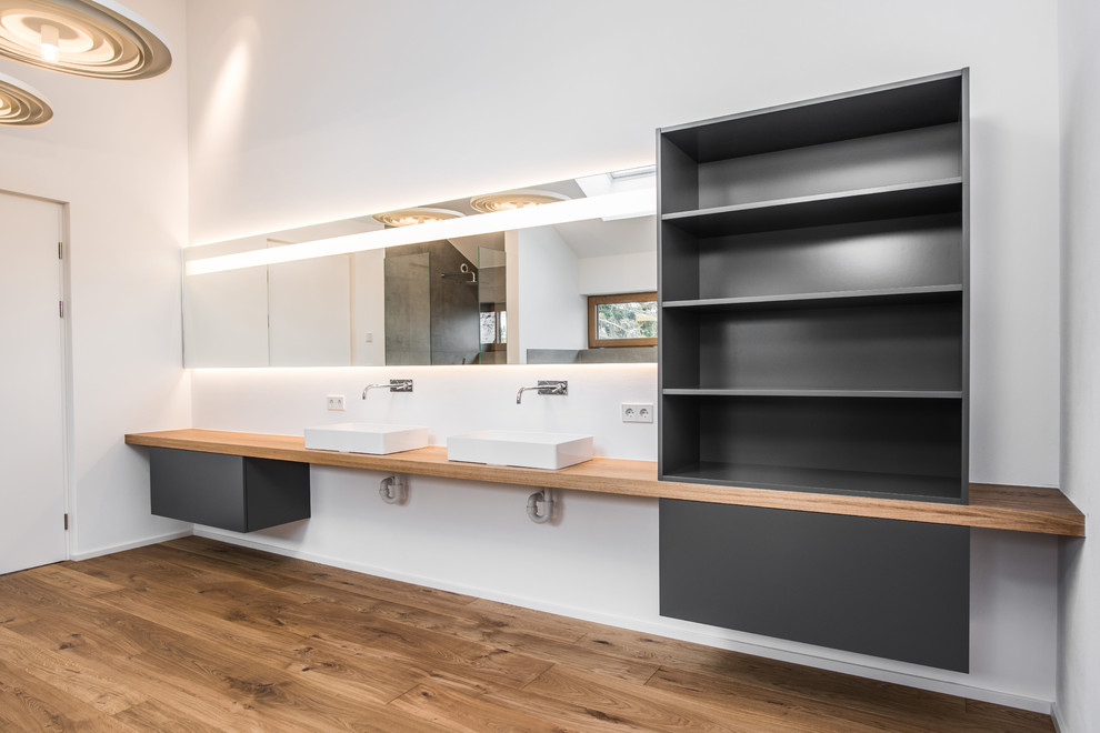 Inspiration for a large contemporary bathroom in Stuttgart with open cabinets, black cabinets, white walls, medium hardwood floors, a vessel sink, wood benchtops, brown floor and brown benchtops.