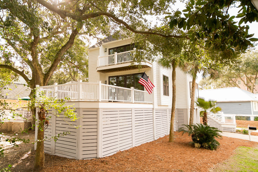 This is an example of a beach style white house exterior in Charleston with a shingle roof.