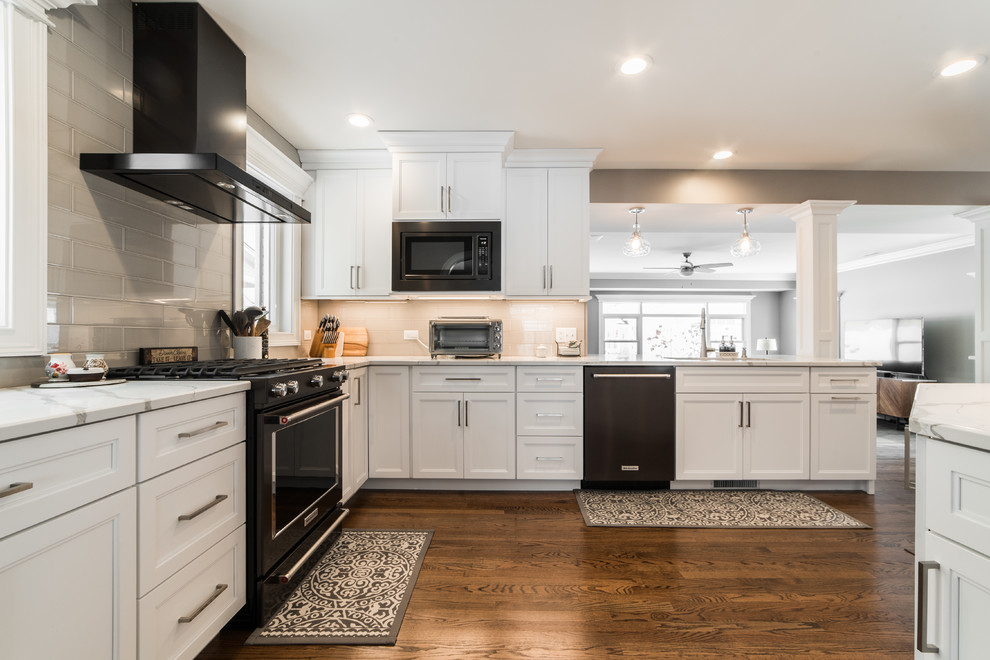 Mid-sized transitional l-shaped medium tone wood floor and brown floor eat-in kitchen photo in Chicago with an undermount sink, recessed-panel cabinets, white cabinets, quartzite countertops, gray backsplash, subway tile backsplash, black appliances, no island and multicolored countertops