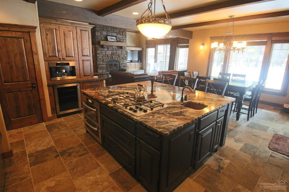 Example of a large arts and crafts l-shaped slate floor and multicolored floor eat-in kitchen design with an undermount sink, raised-panel cabinets, dark wood cabinets, granite countertops, multicolored backsplash, slate backsplash, stainless steel appliances, an island and multicolored countertops