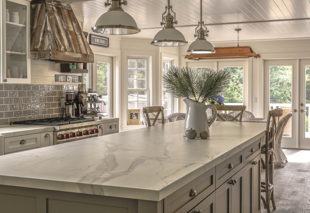 Large country l-shaped eat-in kitchen in San Francisco with a farmhouse sink, white cabinets, grey splashback, ceramic splashback, stainless steel appliances, medium hardwood floors, with island and shaker cabinets.