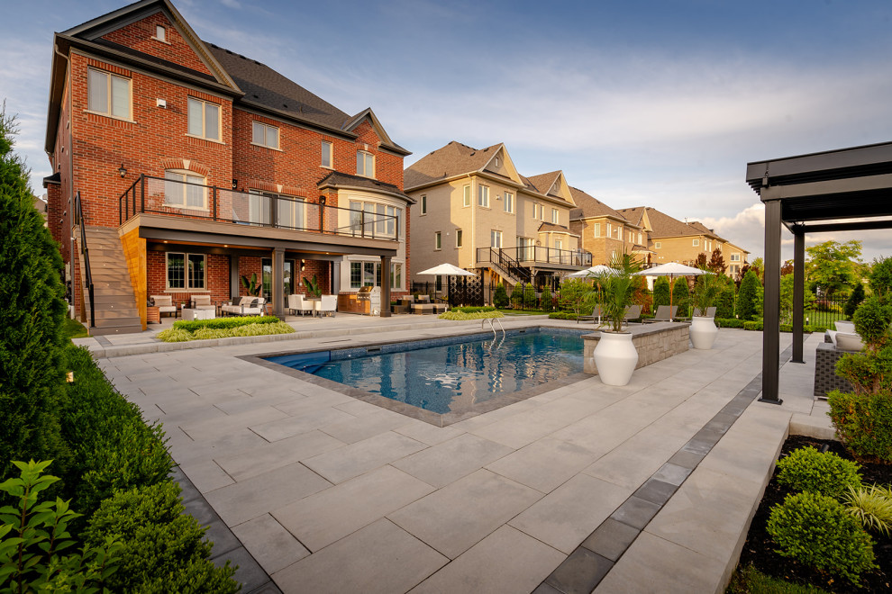 Example of a large transitional backyard concrete paver and rectangular lap pool landscaping design in Toronto