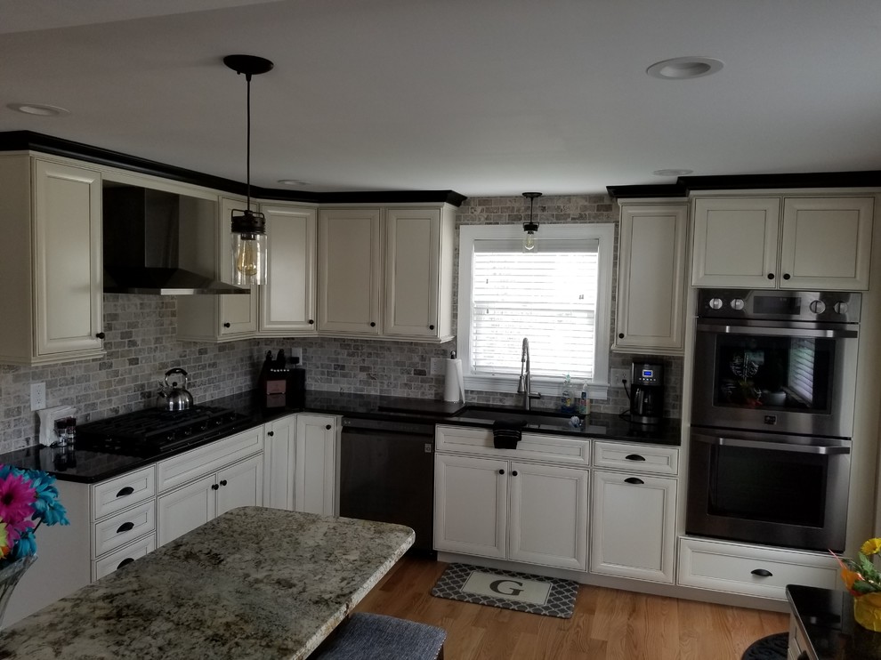 This is an example of an eat-in kitchen in Boston with raised-panel cabinets, white cabinets, granite benchtops, multi-coloured splashback, stainless steel appliances, medium hardwood floors, with island and pink benchtop.