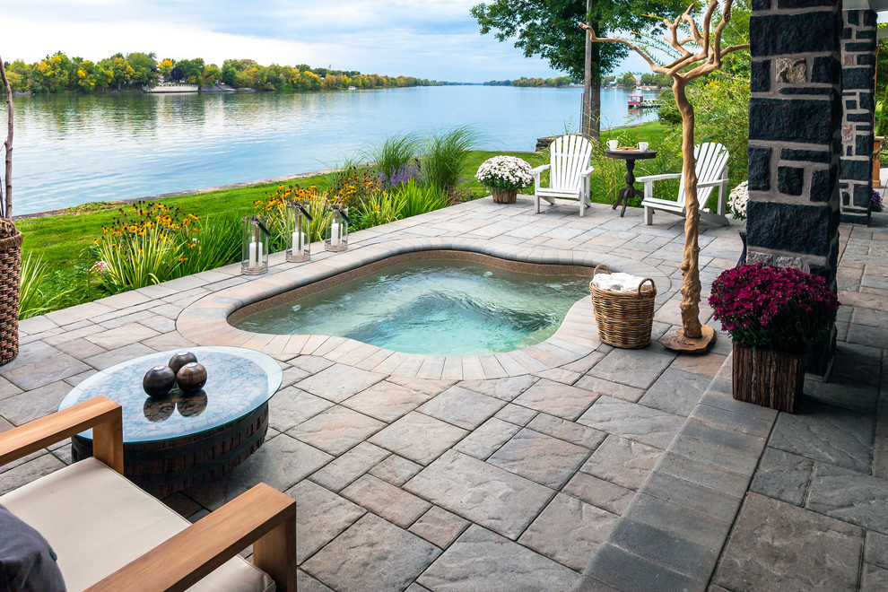 Design ideas for a traditional backyard custom-shaped pool in Other with a hot tub and natural stone pavers.