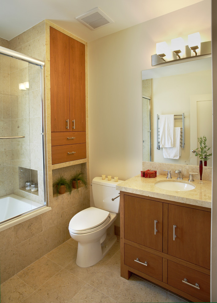 Inspiration for a small contemporary 3/4 bathroom in San Francisco with an undermount sink, flat-panel cabinets, medium wood cabinets, an alcove tub, a shower/bathtub combo, a two-piece toilet, beige tile, limestone benchtops, white walls, limestone floors and travertine.