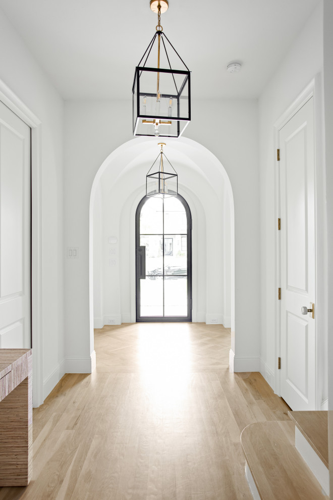 Idées déco pour un grand hall d'entrée classique avec un mur blanc, parquet clair, une porte simple, une porte métallisée et un sol marron.