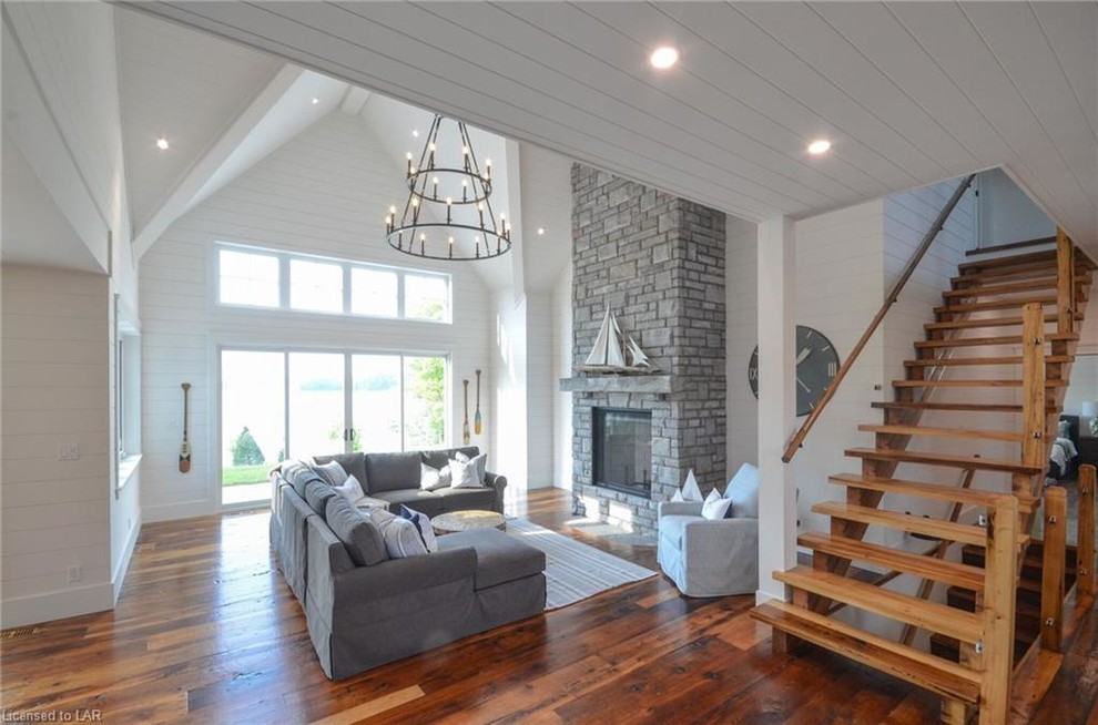 Photo of a mid-sized country formal open concept living room in Toronto with white walls, dark hardwood floors, a standard fireplace, a stone fireplace surround, no tv and brown floor.