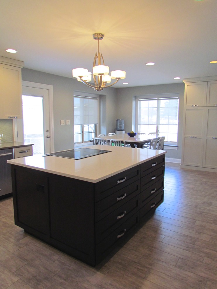 Inspiration for a transitional l-shaped porcelain tile eat-in kitchen remodel in Chicago with a farmhouse sink, shaker cabinets, white cabinets, quartz countertops, blue backsplash, glass tile backsplash, stainless steel appliances and an island