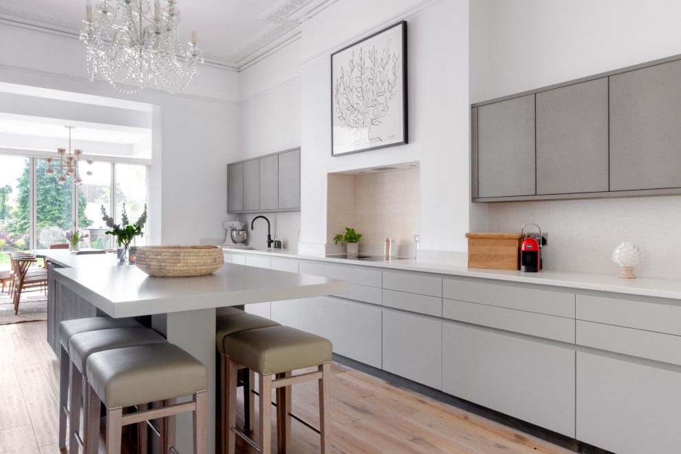 Große Moderne Wohnküche mit flächenbündigen Schrankfronten, grauen Schränken, Quarzit-Arbeitsplatte, Küchenrückwand in Weiß, Kücheninsel und weißer Arbeitsplatte in Gloucestershire