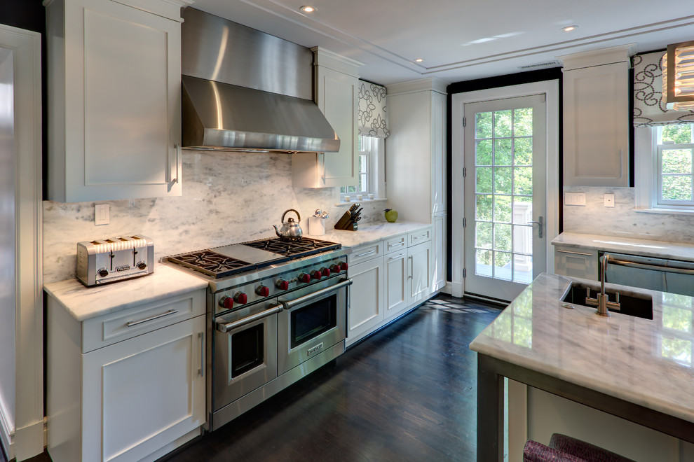 This is an example of a large transitional l-shaped eat-in kitchen in DC Metro with an undermount sink, shaker cabinets, white cabinets, marble benchtops, white splashback, marble splashback, stainless steel appliances, dark hardwood floors, with island, brown floor and white benchtop.