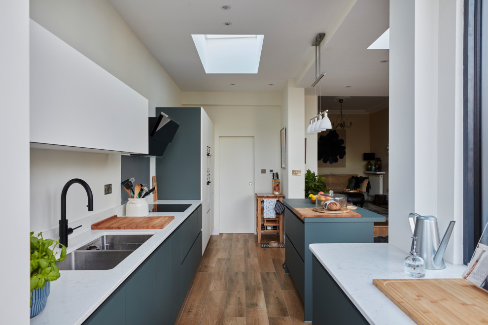 Idéer för ett modernt kök, med en nedsänkt diskho, släta luckor, grå skåp, vitt stänkskydd, mellanmörkt trägolv, en köksö och brunt golv