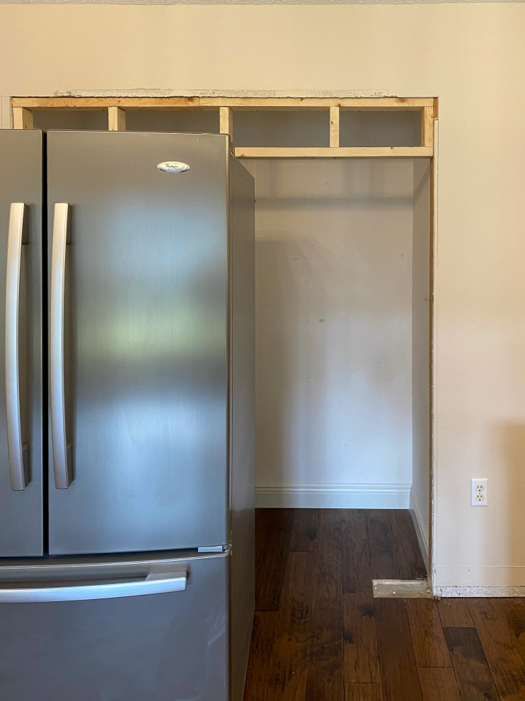 Example of a small transitional single-wall medium tone wood floor, brown floor and vaulted ceiling kitchen pantry design with flat-panel cabinets, dark wood cabinets, marble countertops, stainless steel appliances and white countertops