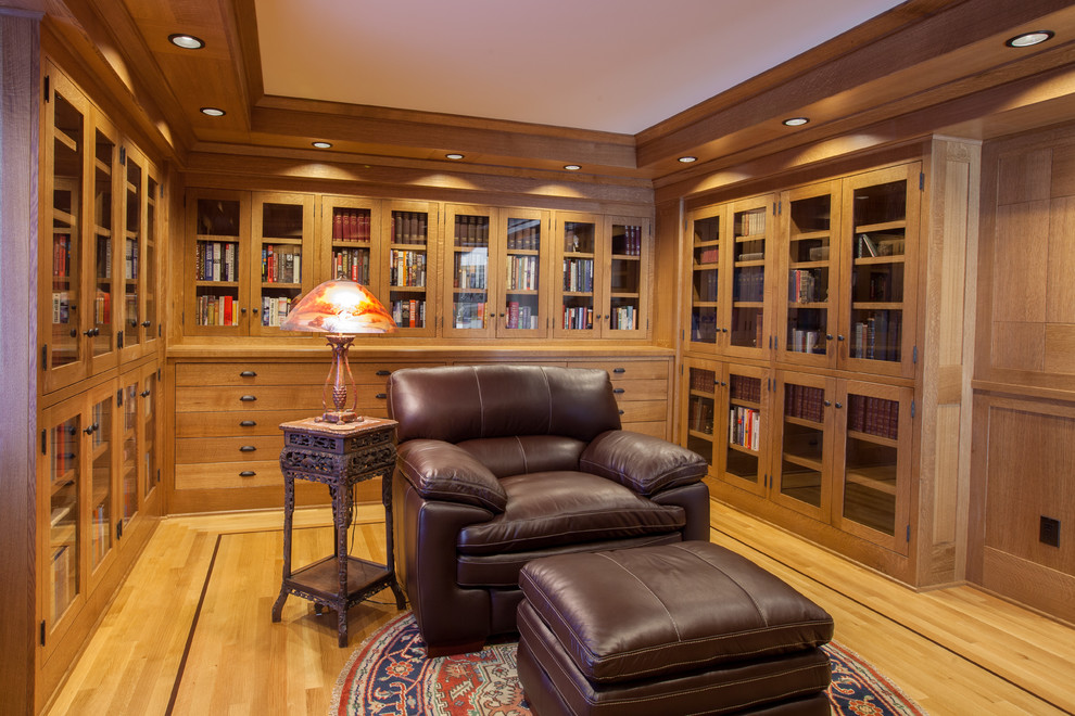 Photo of a mid-sized arts and crafts home office in Portland with a library, brown walls, light hardwood floors, a freestanding desk and brown floor.