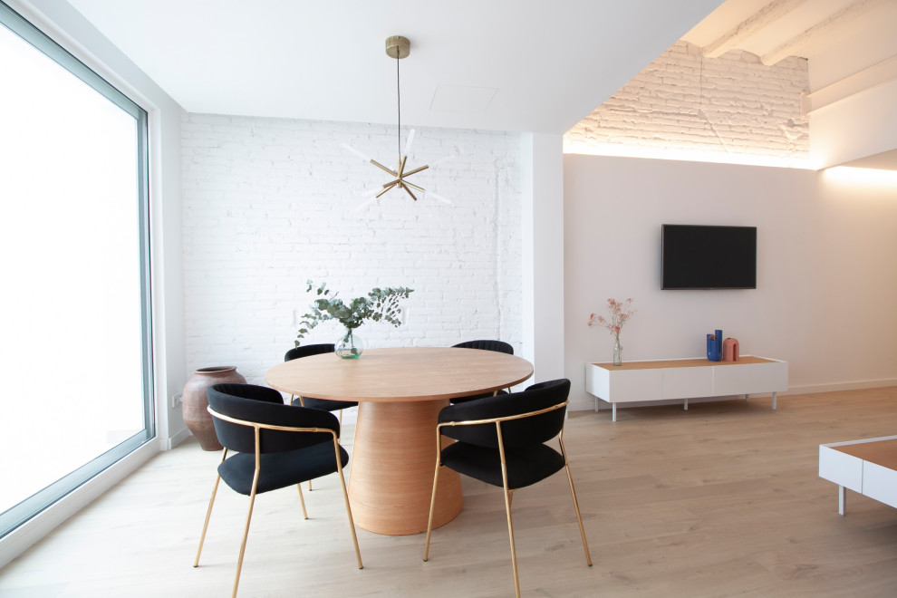 Medium sized contemporary dining room in Barcelona with white walls, laminate floors, no fireplace, brown floors, a vaulted ceiling and brick walls.