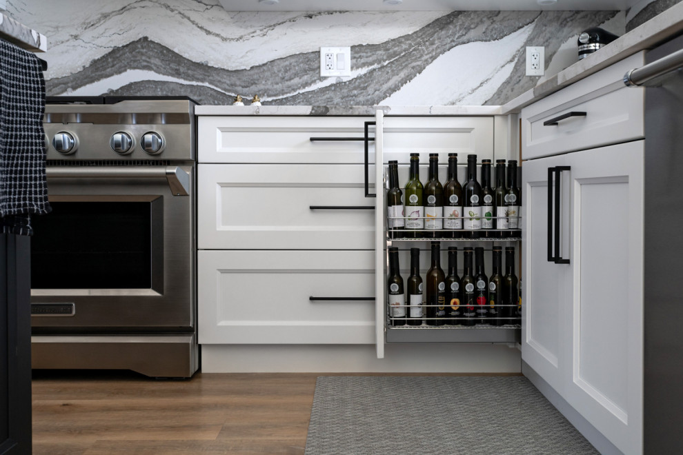 Example of a mid-sized transitional u-shaped medium tone wood floor and brown floor eat-in kitchen design with an undermount sink, recessed-panel cabinets, white cabinets, quartz countertops, white backsplash, stone slab backsplash, stainless steel appliances, an island and white countertops